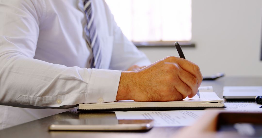 Businessman Writing Notes at Office Desk In Daylight - Free Images, Stock Photos and Pictures on Pikwizard.com