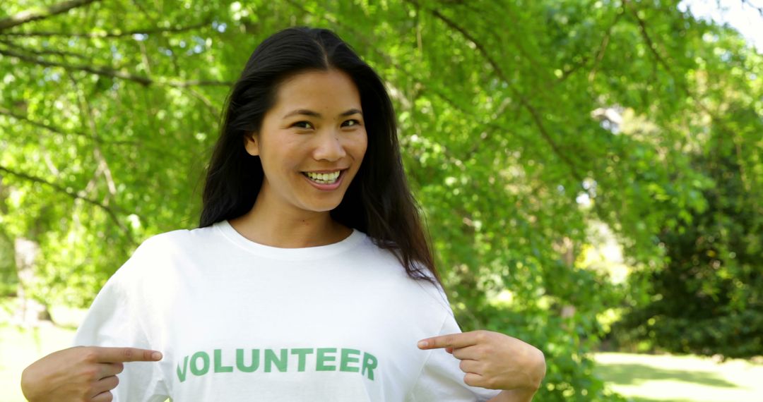 Smiling Woman in Volunteer T-Shirt Pointing to Slogan Outdoors - Free Images, Stock Photos and Pictures on Pikwizard.com