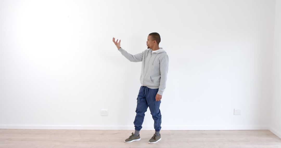 Man in Casual Wear Gesturing Energetically Against White Wall