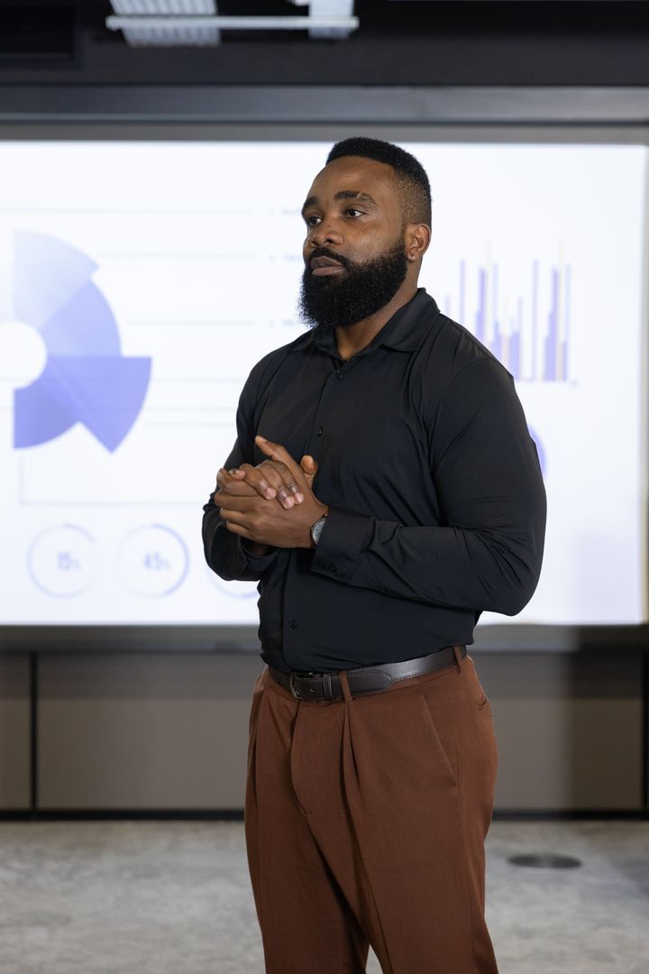 African American Presenter in Business Meeting with Projected Charts