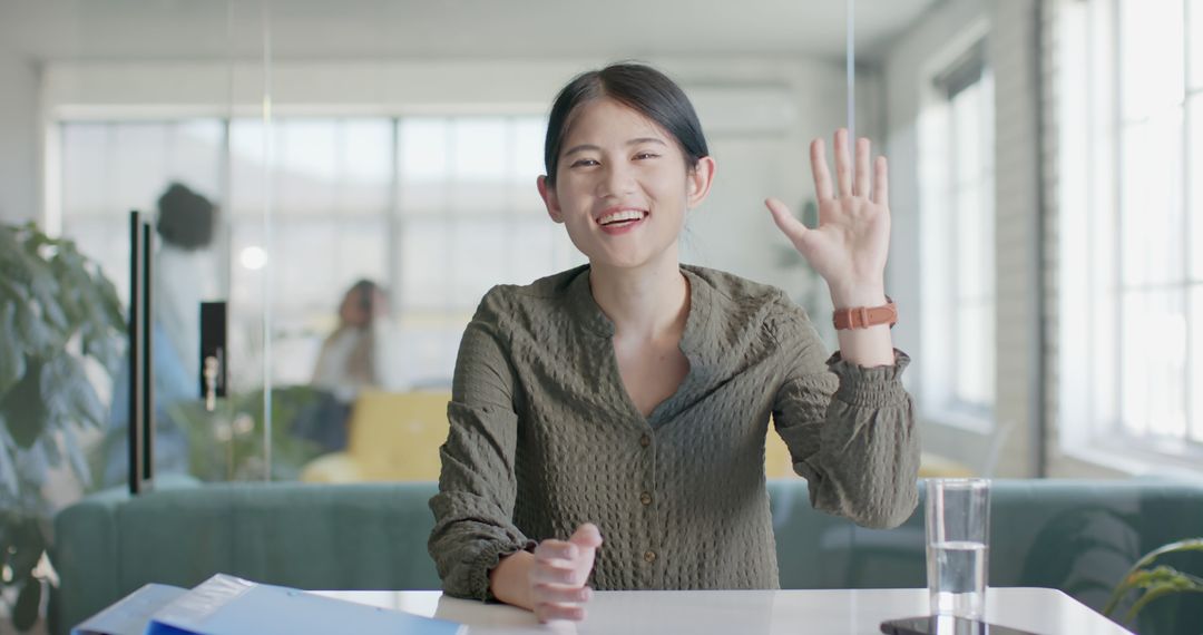 Businesswoman Waving in Modern Office During Video Call - Free Images, Stock Photos and Pictures on Pikwizard.com