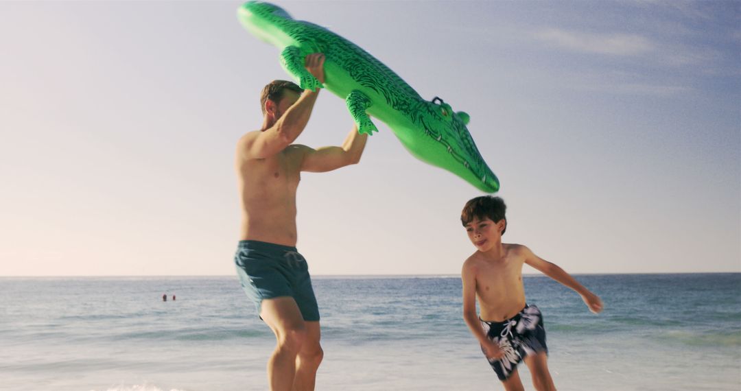 Father and Son Playing with Inflatable Crocodile on Beach - Free Images, Stock Photos and Pictures on Pikwizard.com