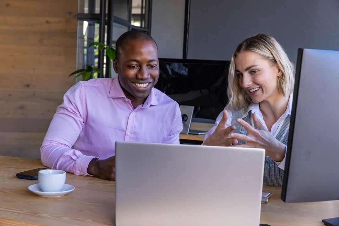 Diverse Coworkers Collaborating at Office Desk on Laptop