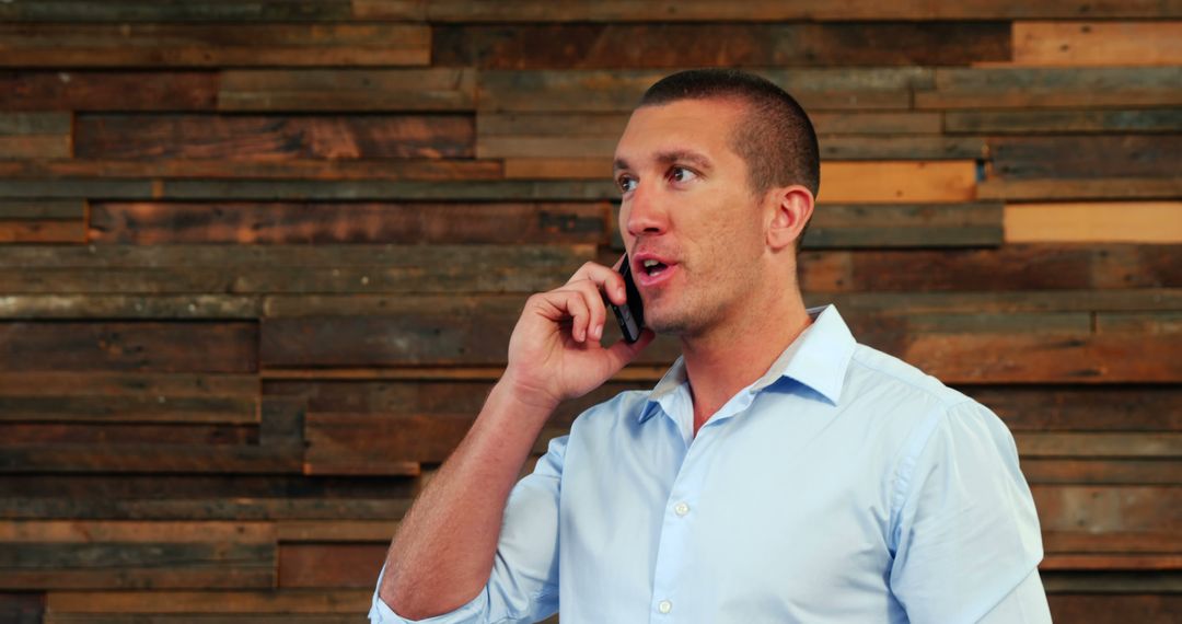 Young Professional Talking on Phone in Front of Wooden Wall - Free Images, Stock Photos and Pictures on Pikwizard.com