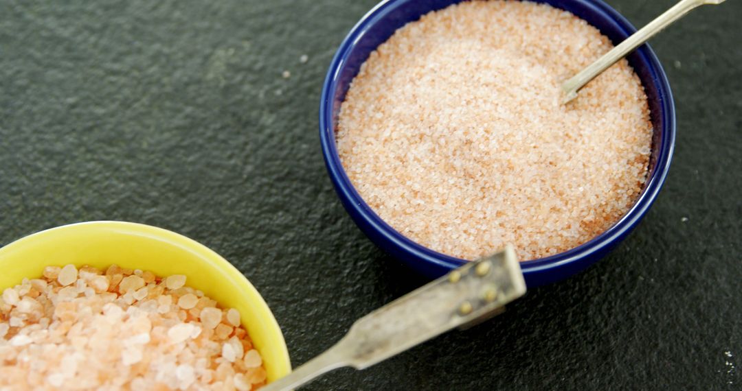 Close-Up of Pink Himalayan Salt in Bowls with Spoons on Black Surface - Free Images, Stock Photos and Pictures on Pikwizard.com