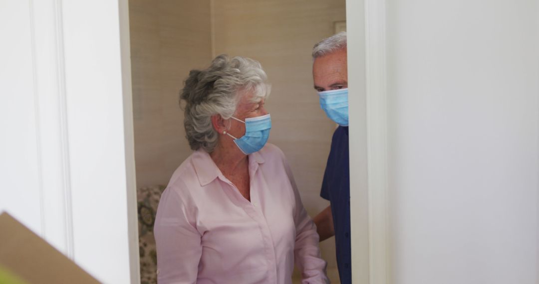 Senior caucasian couple in face masks receiving delivery at front door of home - Free Images, Stock Photos and Pictures on Pikwizard.com