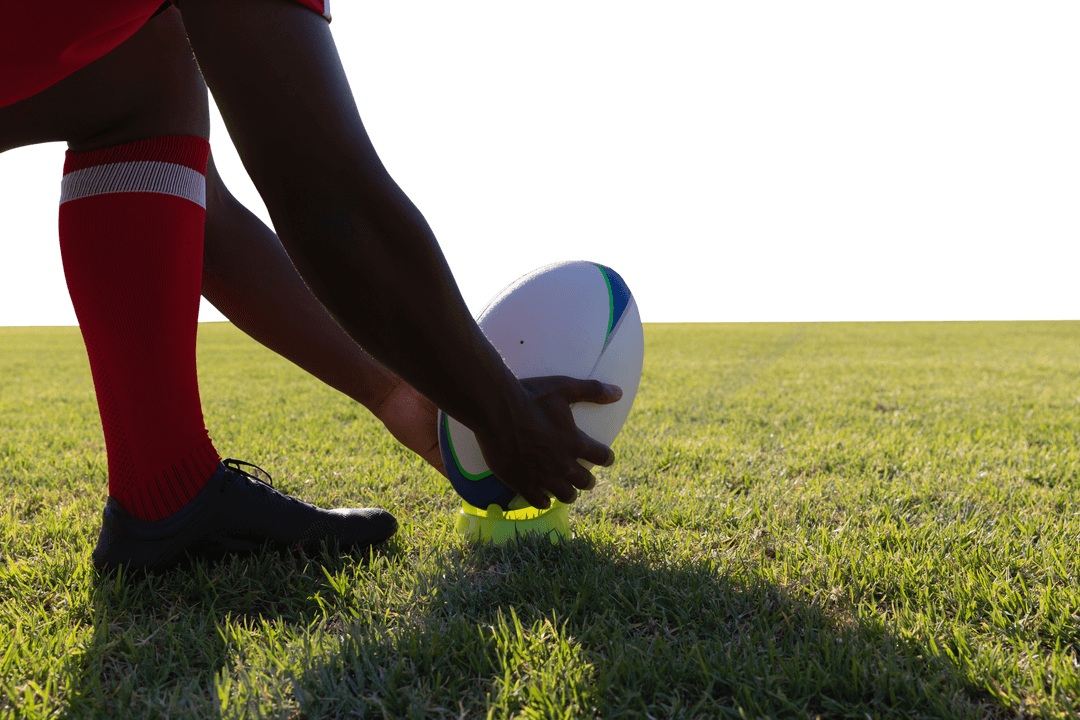 Rugby Player Placing Ball on Grassy Field Under Transparent Sky
