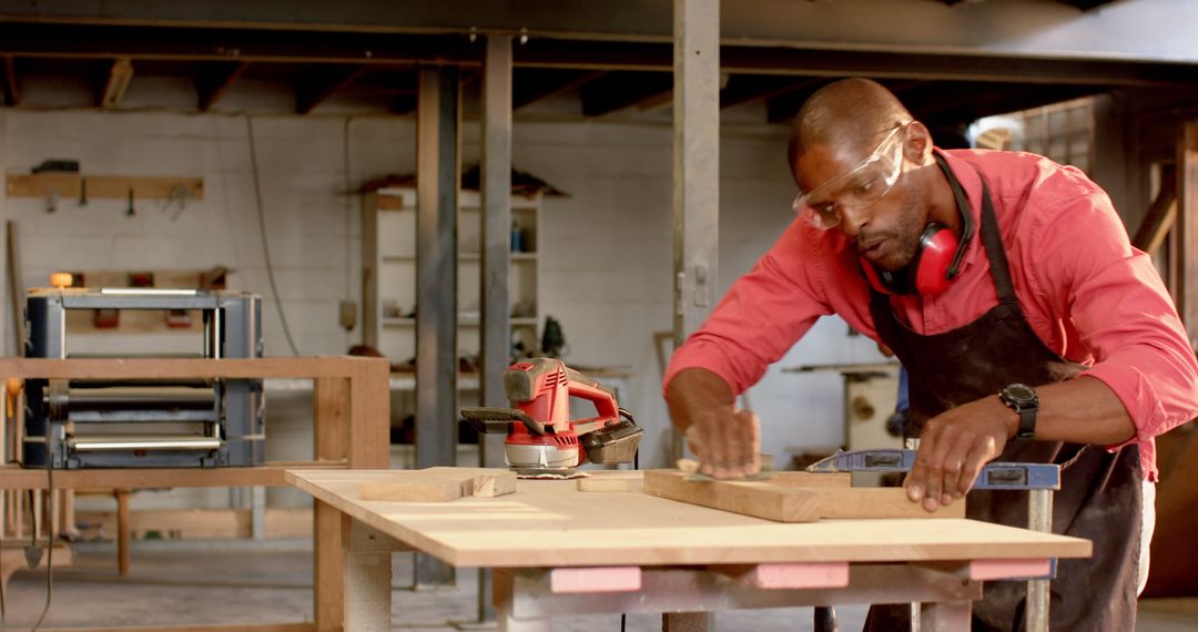 Skilled Woodworker Sanding Wooden Plank in Workshop