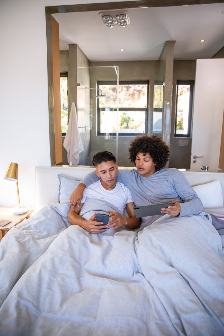 Couple Relaxing in Modern Bedroom with Devices
