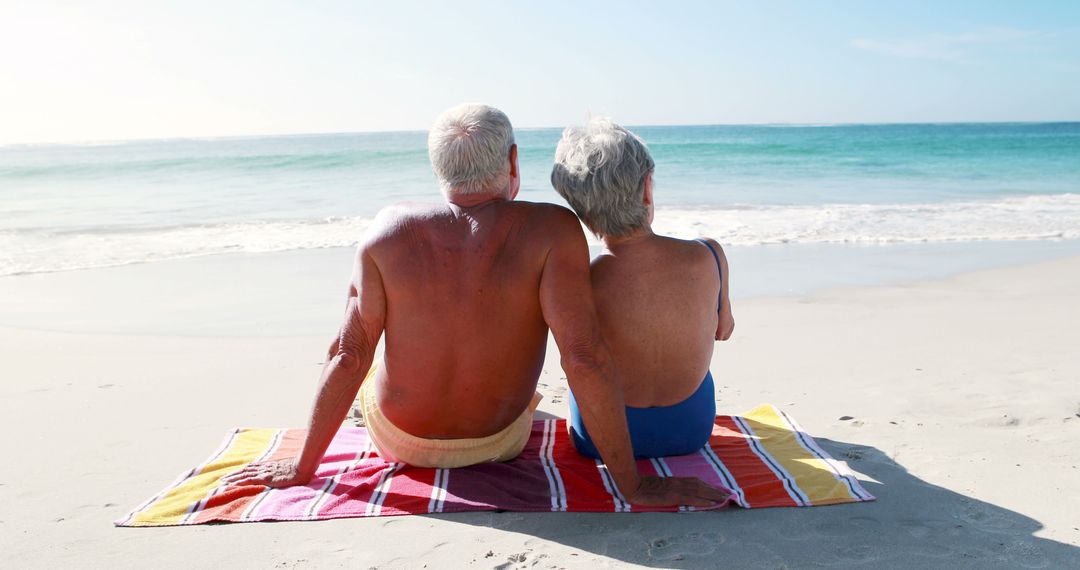 Senior Couple Relaxing on Beach Towel by Ocean Shore - Free Images, Stock Photos and Pictures on Pikwizard.com