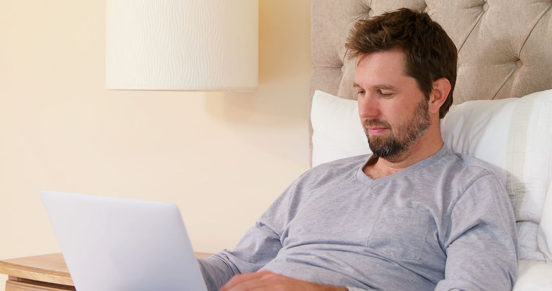 Man Relaxing in Bed While Using Laptop for Remote Work - Free Images, Stock Photos and Pictures on Pikwizard.com