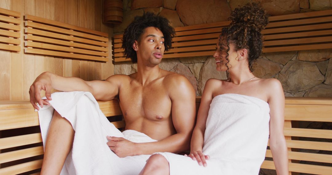 Image of relaxed diverse couple wearing towels sitting and talking in sauna room at health spa - Free Images, Stock Photos and Pictures on Pikwizard.com