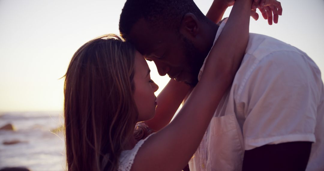 Biracial couple shares a tender moment on the beach at sunset - Free Images, Stock Photos and Pictures on Pikwizard.com