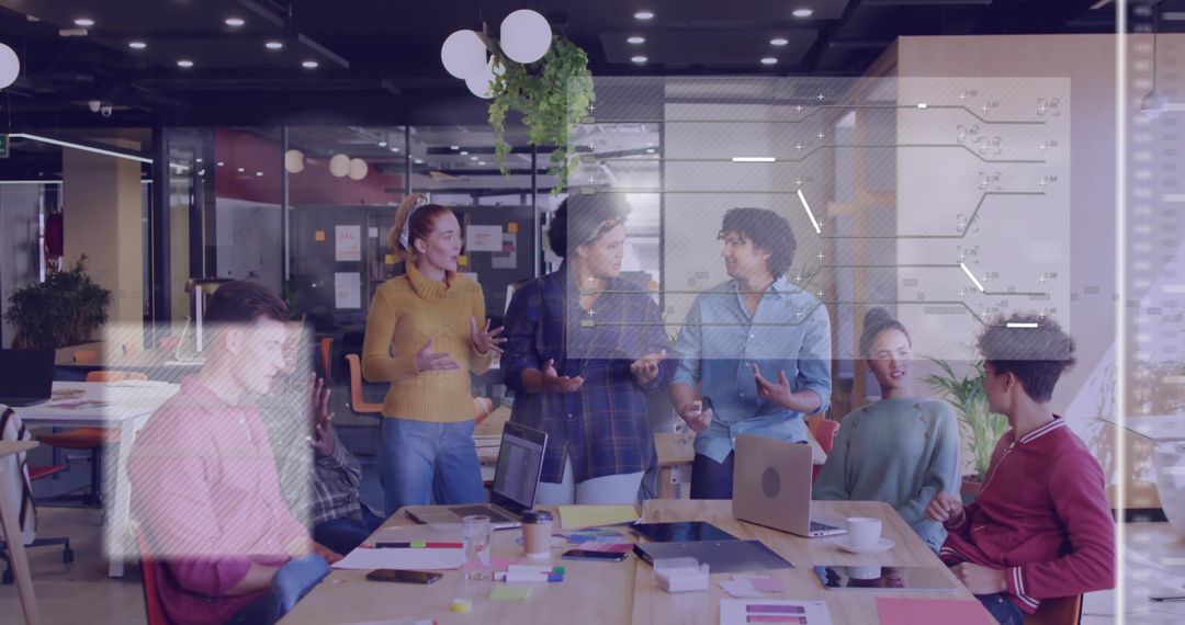 Diverse Team Brainstorming in Modern Startup Office Around Table with Laptops