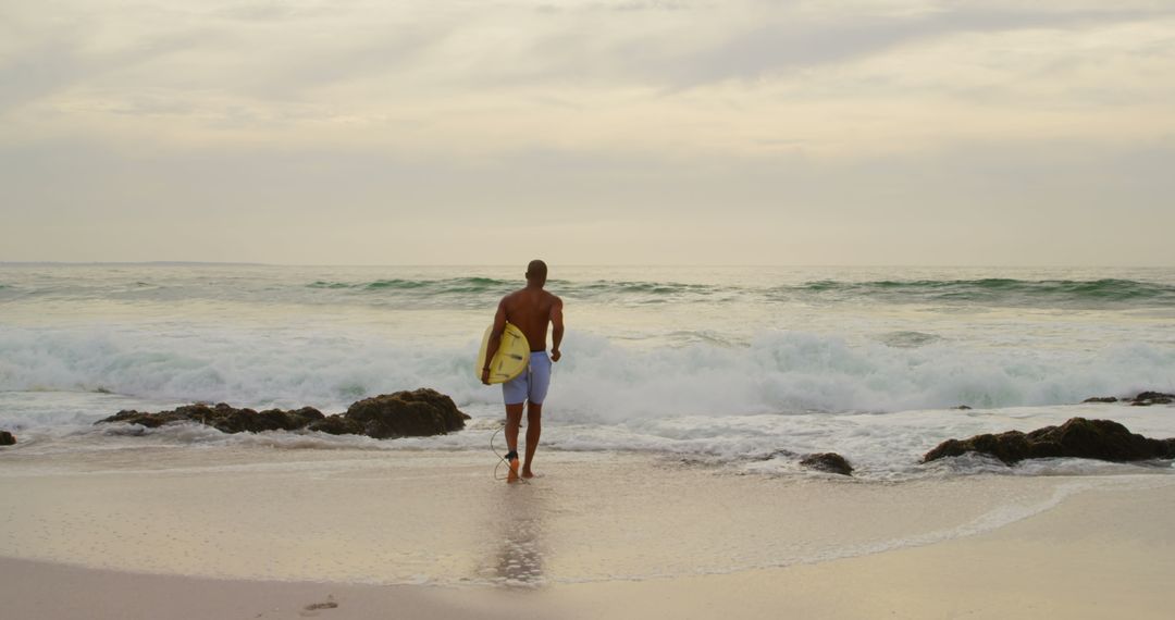 Surfer Approaching Ocean with Surfboard at Serene Sunrise Beach