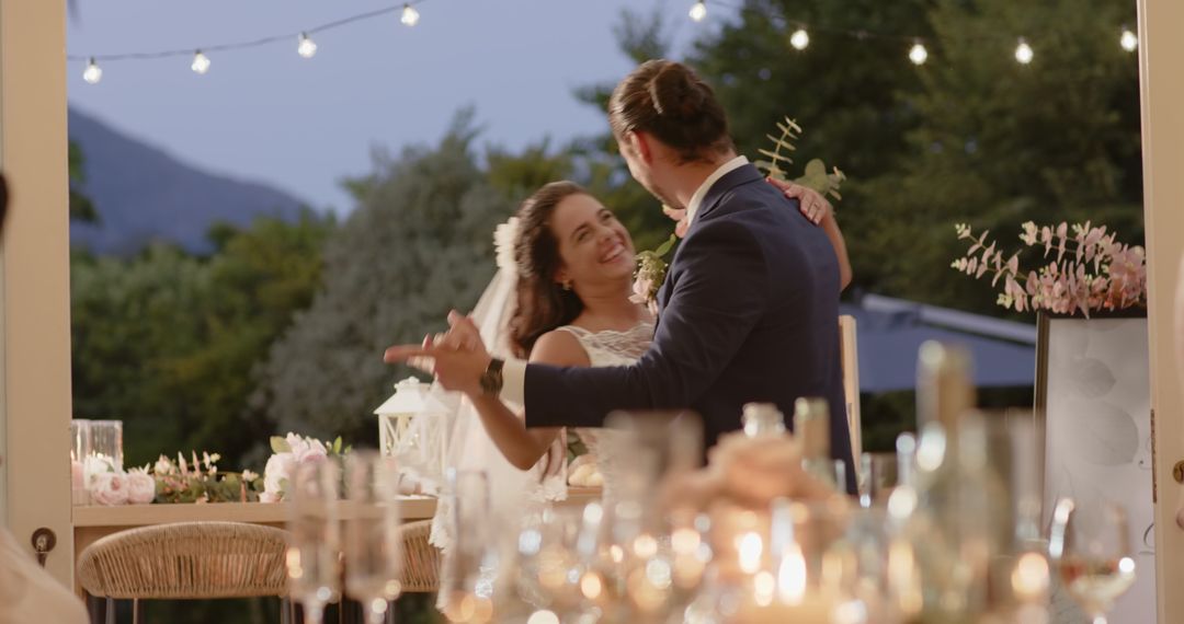 Bride and Groom Dancing Under Twinkling Lights at Romantic Evening Reception