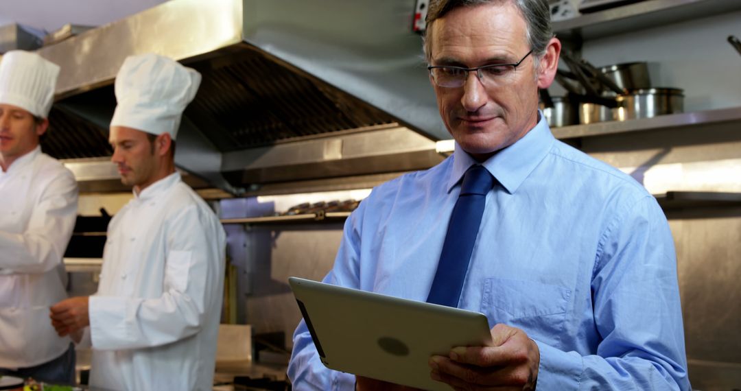 Manager overseeing kitchen staff with digital tablet - Free Images, Stock Photos and Pictures on Pikwizard.com