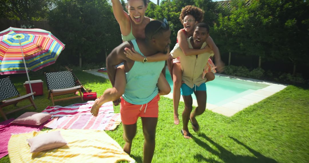 Diverse Friends Having Fun Poolside with Piggyback Rides and Picnic Setup