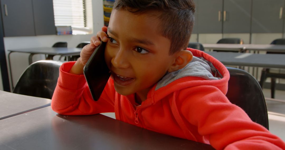 Smiling Schoolboy Talking on Mobile Phone in Classroom