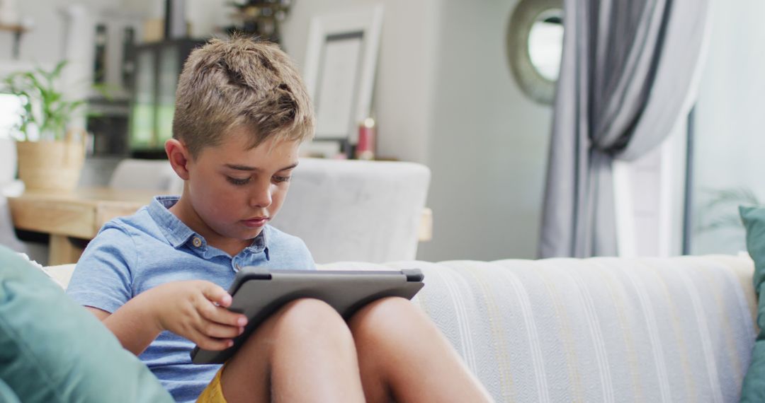 Focused Young Boy Using Tablet on Sofa at Home - Free Images, Stock Photos and Pictures on Pikwizard.com