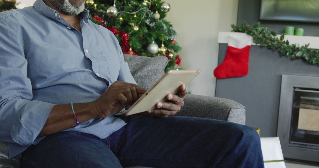 Man Using Tablet near Christmas Tree in Cozy Living Room - Free Images, Stock Photos and Pictures on Pikwizard.com