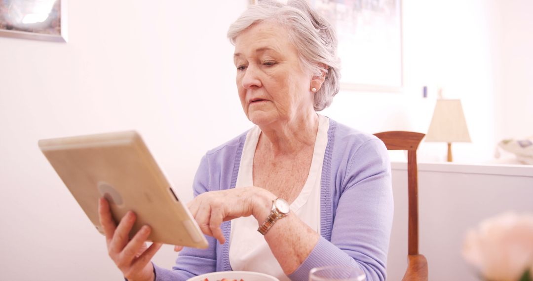 Senior Woman Using Tablet at Home While Eating Breakfast - Free Images, Stock Photos and Pictures on Pikwizard.com