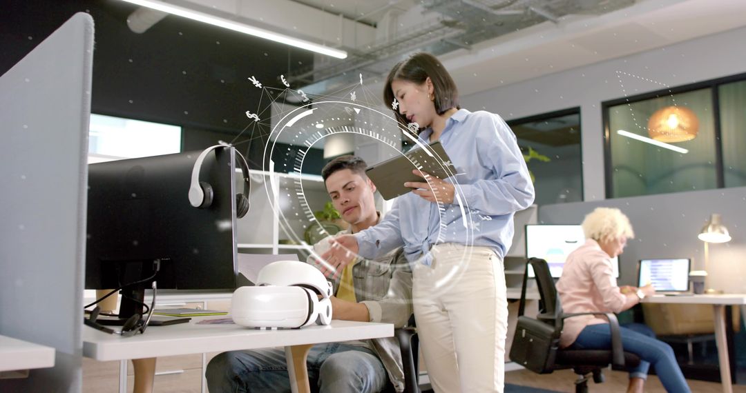 Hispanic man and Asian woman collaborating with tablet beside VR headset in modern office