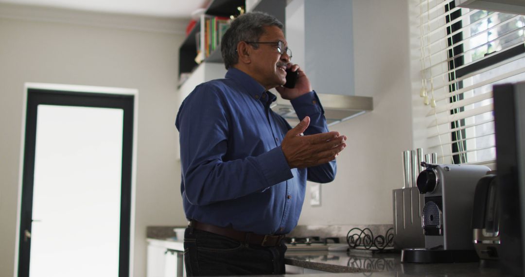 Mature Man Talking on Telephone in Modern Kitchen - Free Images, Stock Photos and Pictures on Pikwizard.com