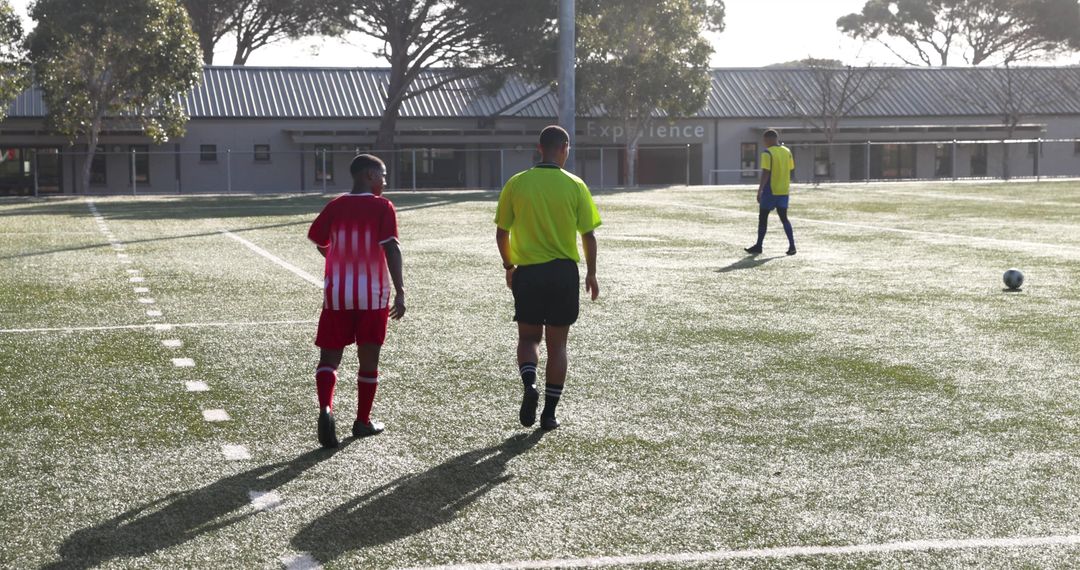 Soccer Referee and Players Walking on Field during Training Session