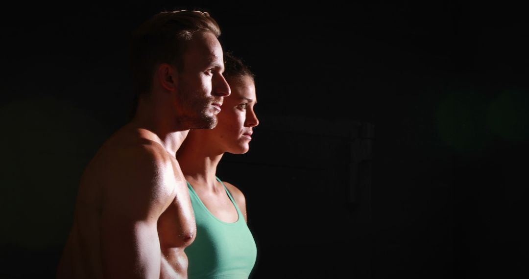 Profile of athletic man and woman posing in dark studio - Free Images, Stock Photos and Pictures on Pikwizard.com