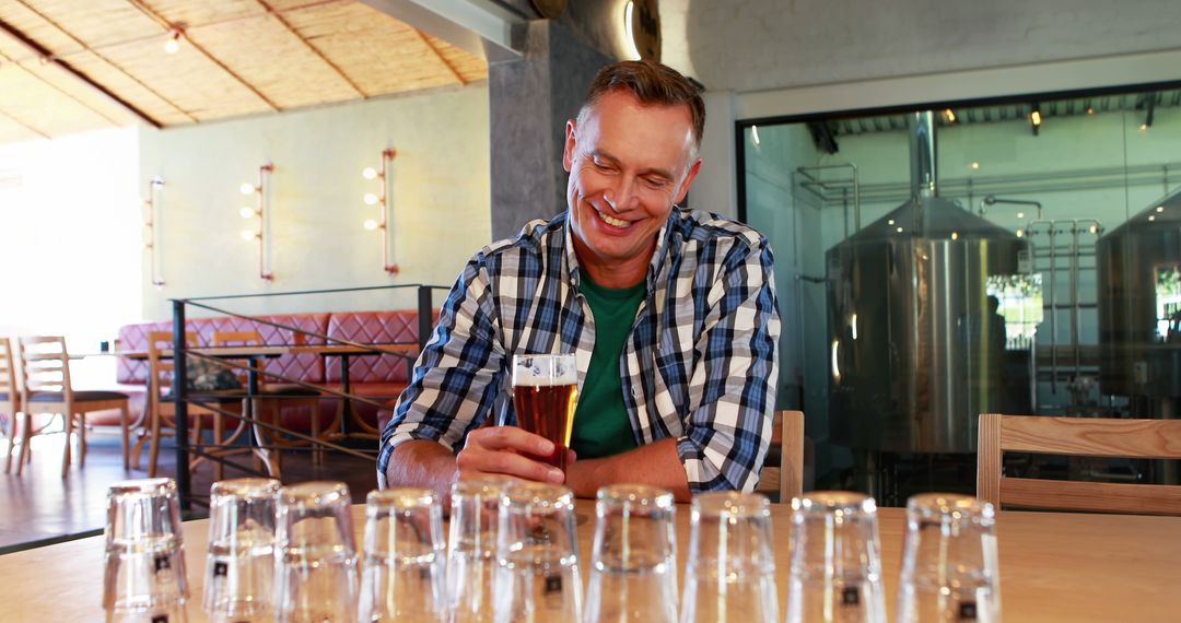 A middle-aged Caucasian man smiles as he enjoys a glass of beer in a brewery, with copy space - Free Images, Stock Photos and Pictures on Pikwizard.com