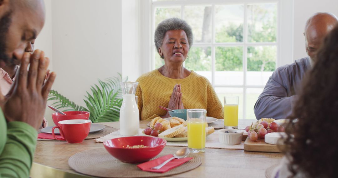 Image of happy african american parents, daughter and grandparents saying grace at dinner table - Free Images, Stock Photos and Pictures on Pikwizard.com