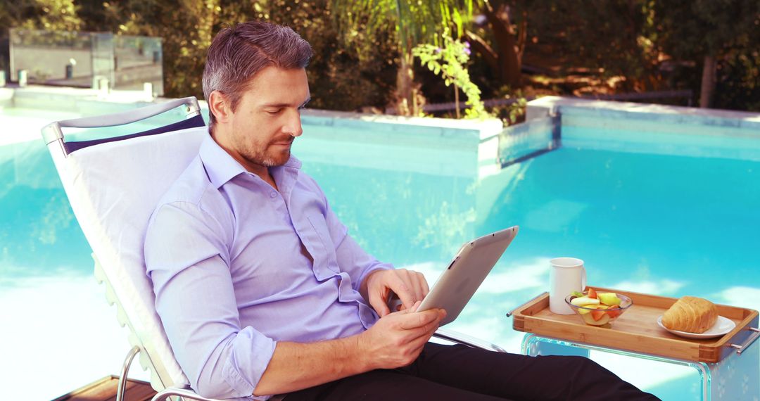 Man Working on Tablet by Outdoor Pool with Breakfast - Free Images, Stock Photos and Pictures on Pikwizard.com