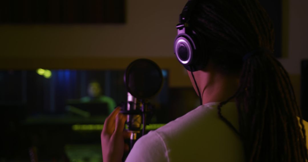 Singer with Headphones Singing in Professional Recording Studio