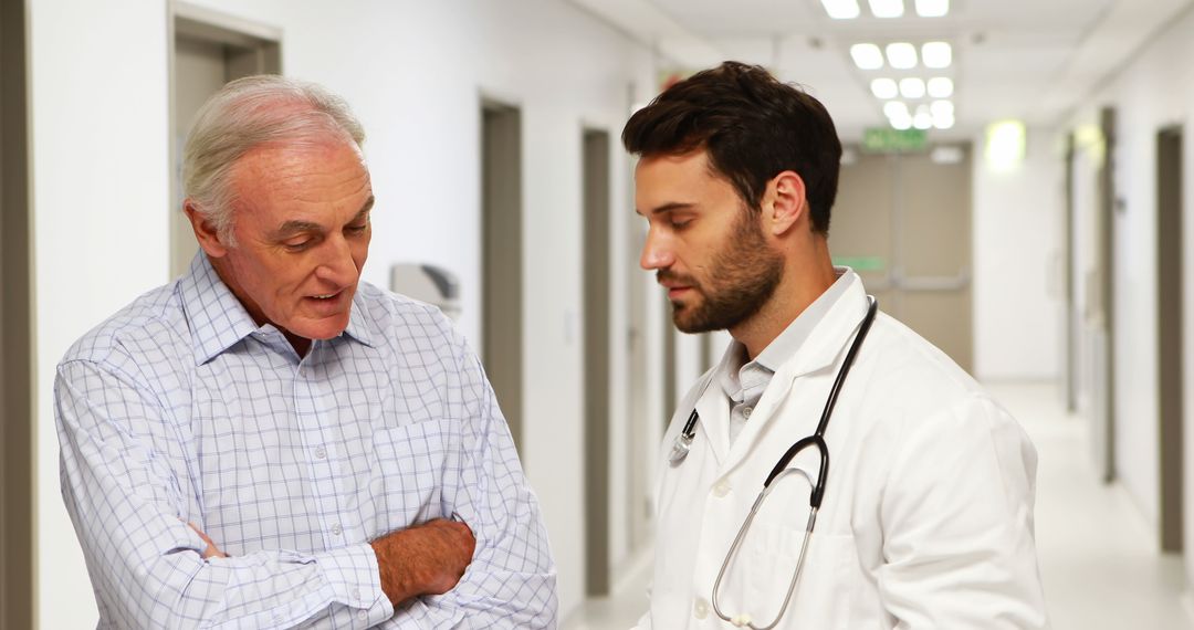 Doctor Discussing Report with Elderly Patient in Hospital Corridor - Free Images, Stock Photos and Pictures on Pikwizard.com