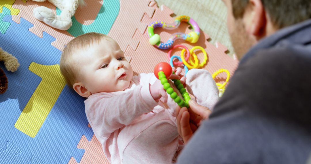 Baby Playing with Toys on Colorful Mat with Father - Free Images, Stock Photos and Pictures on Pikwizard.com