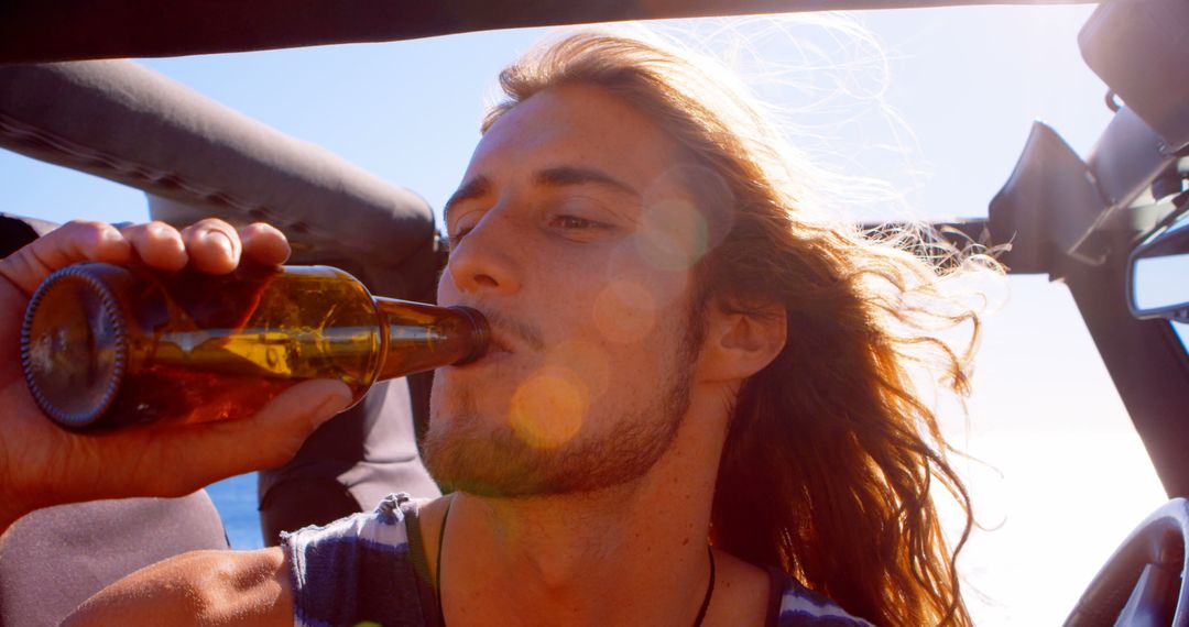 Carefree Young Man Drinking Beer in Open-Top Car - Free Images, Stock Photos and Pictures on Pikwizard.com