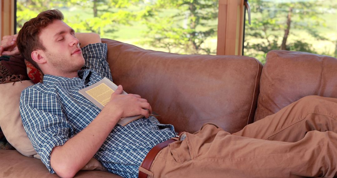 Young Man Relaxing on Couch with Book in Hand - Free Images, Stock Photos and Pictures on Pikwizard.com