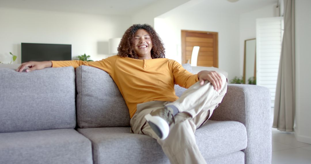 Relaxed Young Man Lounging on Modern Couch in Home - Free Images, Stock Photos and Pictures on Pikwizard.com