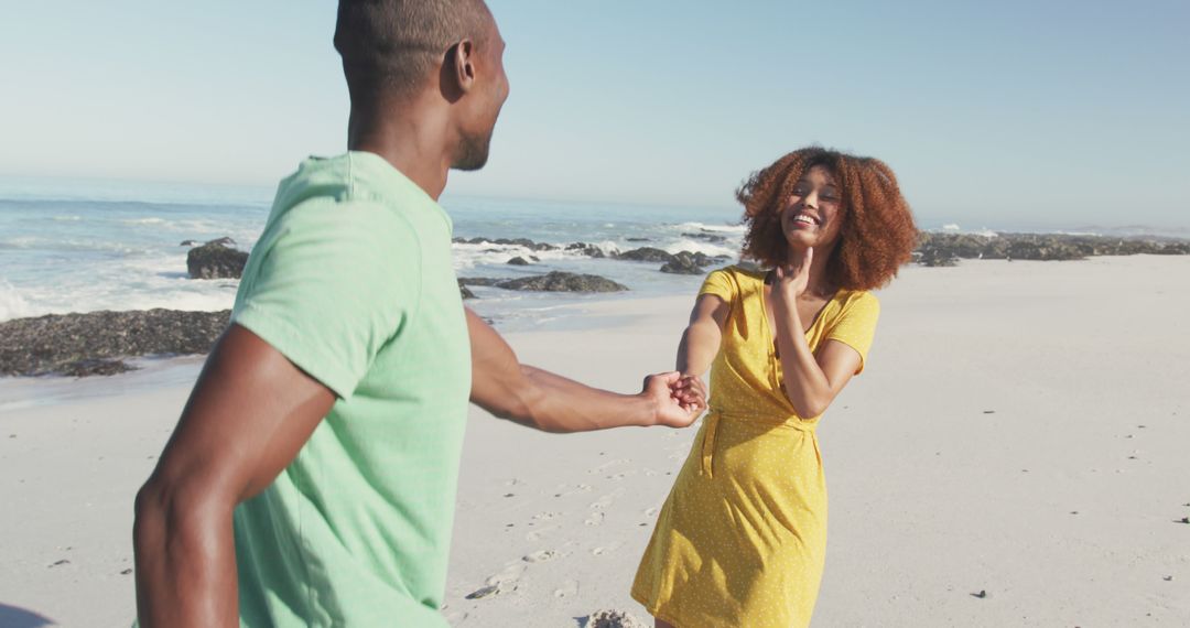 Happy biracial couple standing on beach, holding hands and laughing - Free Images, Stock Photos and Pictures on Pikwizard.com