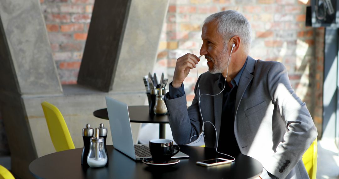 Businessman Enjoying Coffee While Using Laptop in Modern Cafe - Free Images, Stock Photos and Pictures on Pikwizard.com