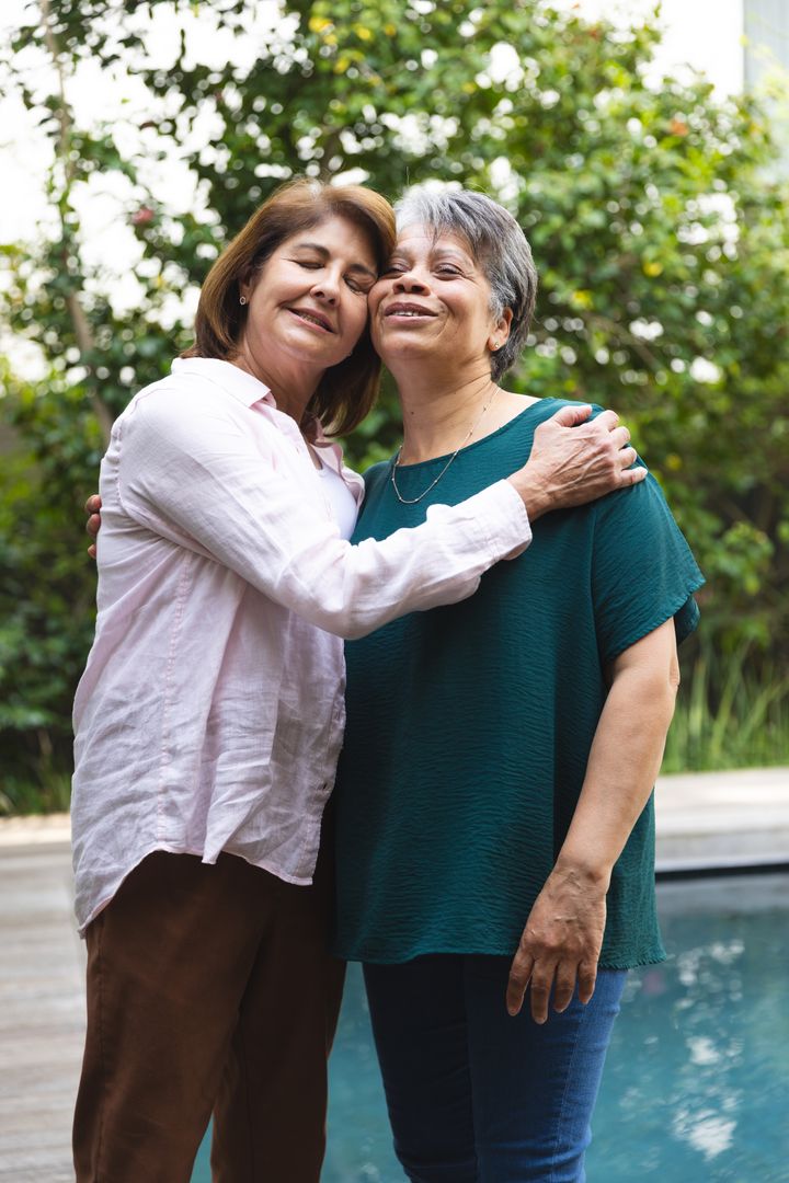 Senior Friends Embracing Beside Pool in Backyard Garden