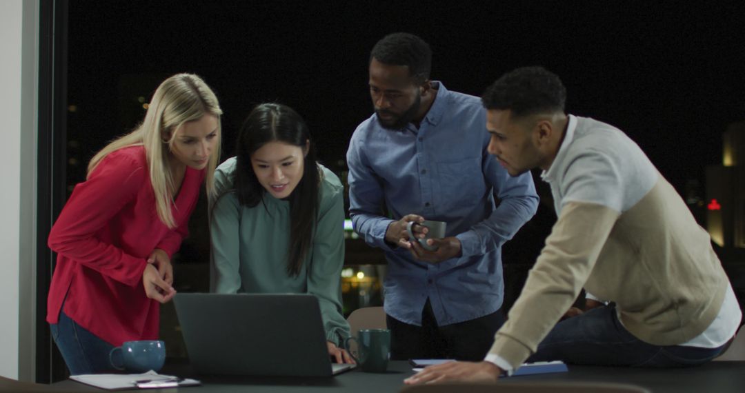 Diverse Team Collaborating on Laptop During Evening in Office