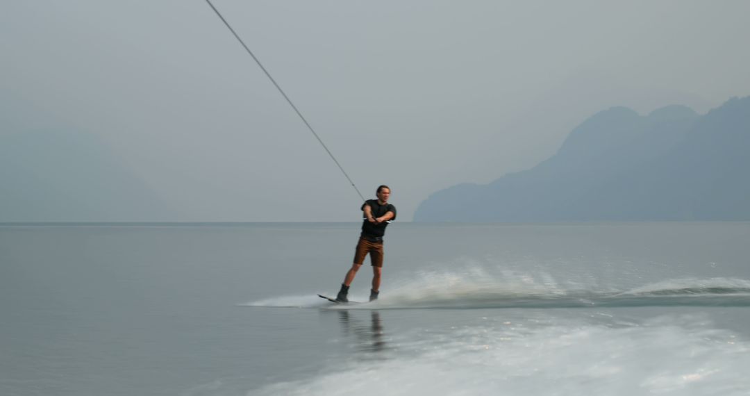 Man Wakeboarding on Misty Lake with Mountain Background - Free Images, Stock Photos and Pictures on Pikwizard.com