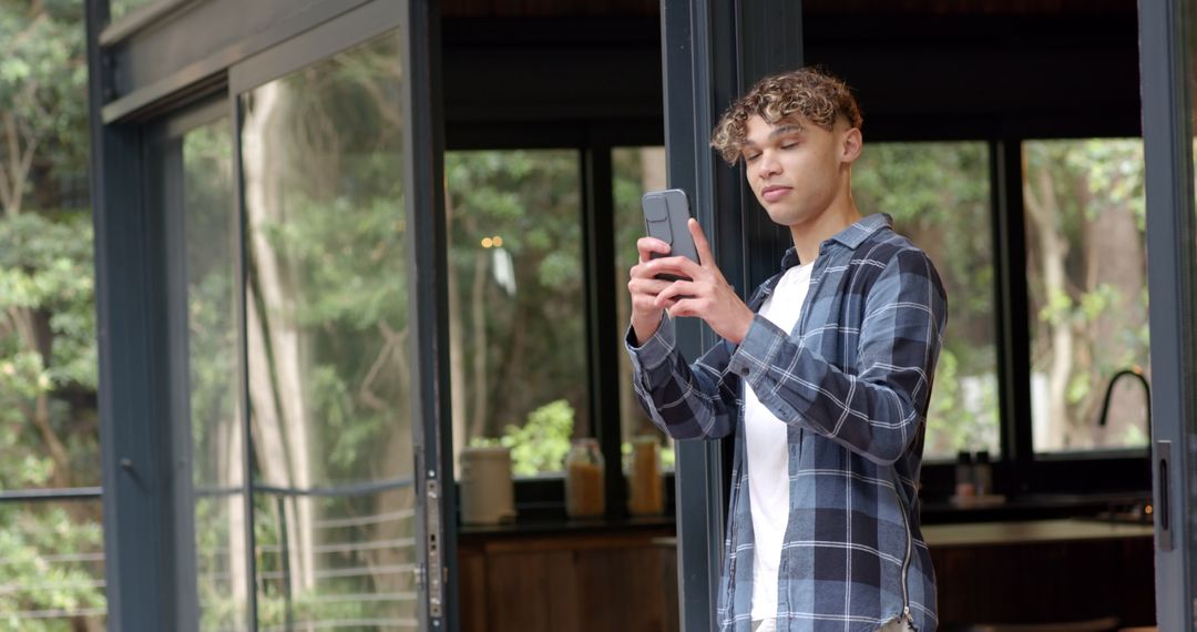 Young Man Using Smartphone on Sunny Deck with Scenic View