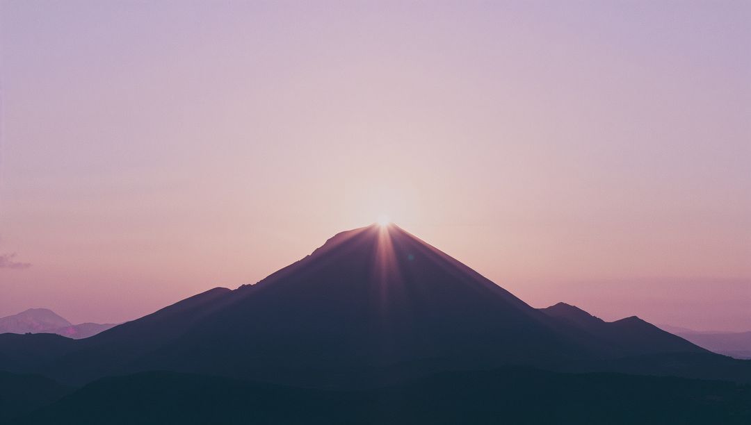 Sunrise Over Mountain Peak with Radiant Sun Rays in Dawn Light