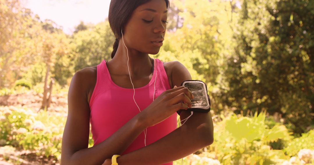 Fit woman using smartphone armband while jogging in park - Free Images, Stock Photos and Pictures on Pikwizard.com