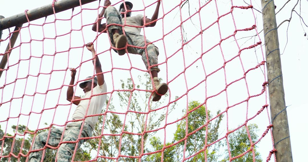Military Personnel Navigating Rope Climb Obstacle with Teamwork