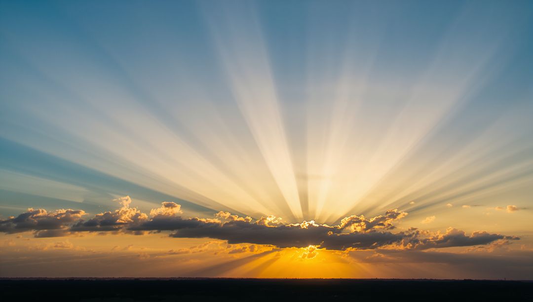 Radiating Sunrise Casting Crepuscular Rays Across Cloud-Held Horizon