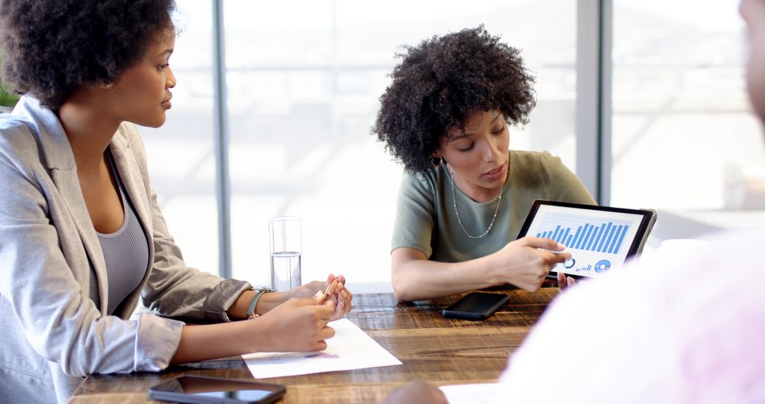 Diverse Team Analyzing Business Data on Tablet in Modern Office